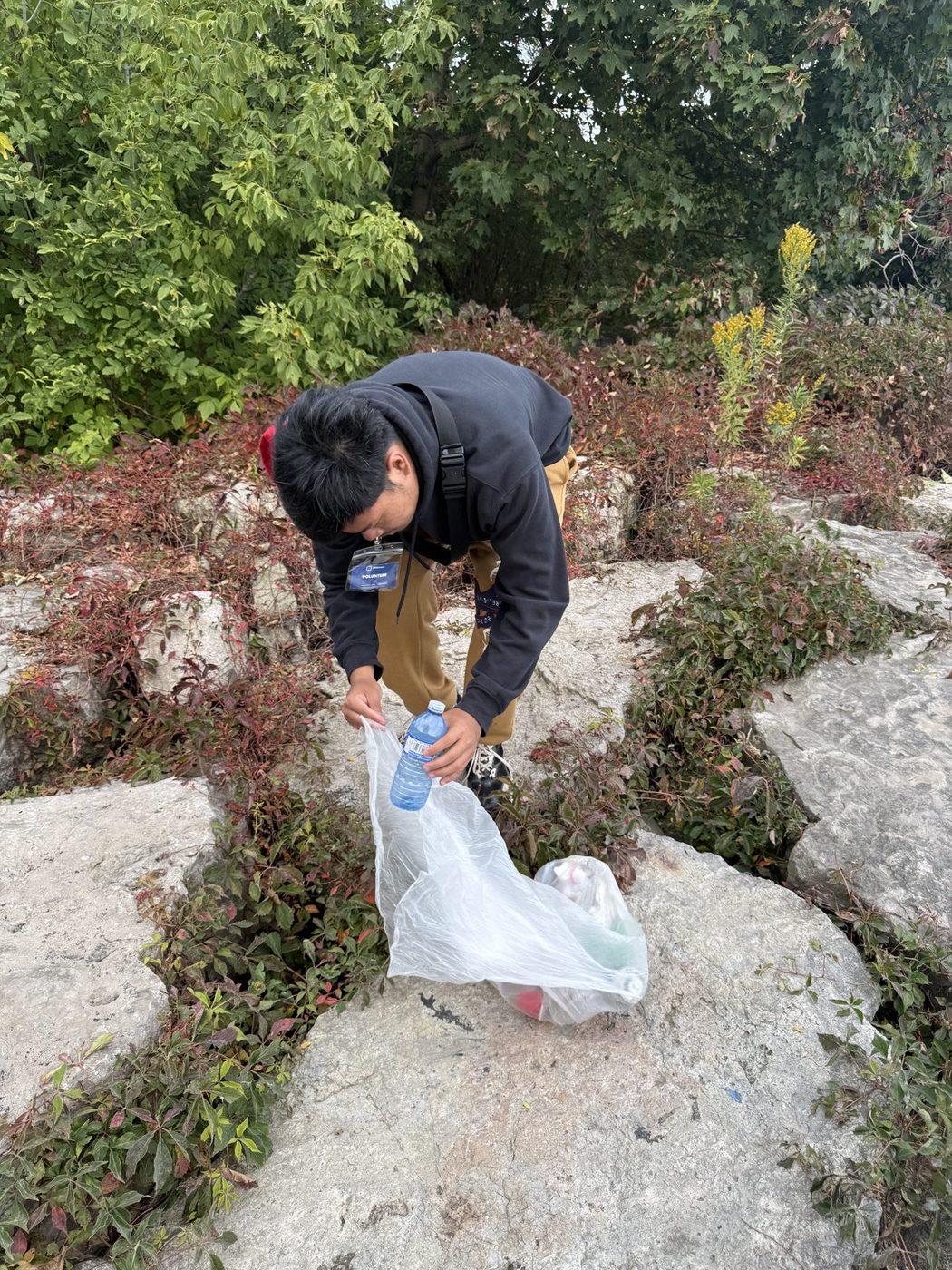 A volunteer picking up litter among rocks during a GTHA park cleanup