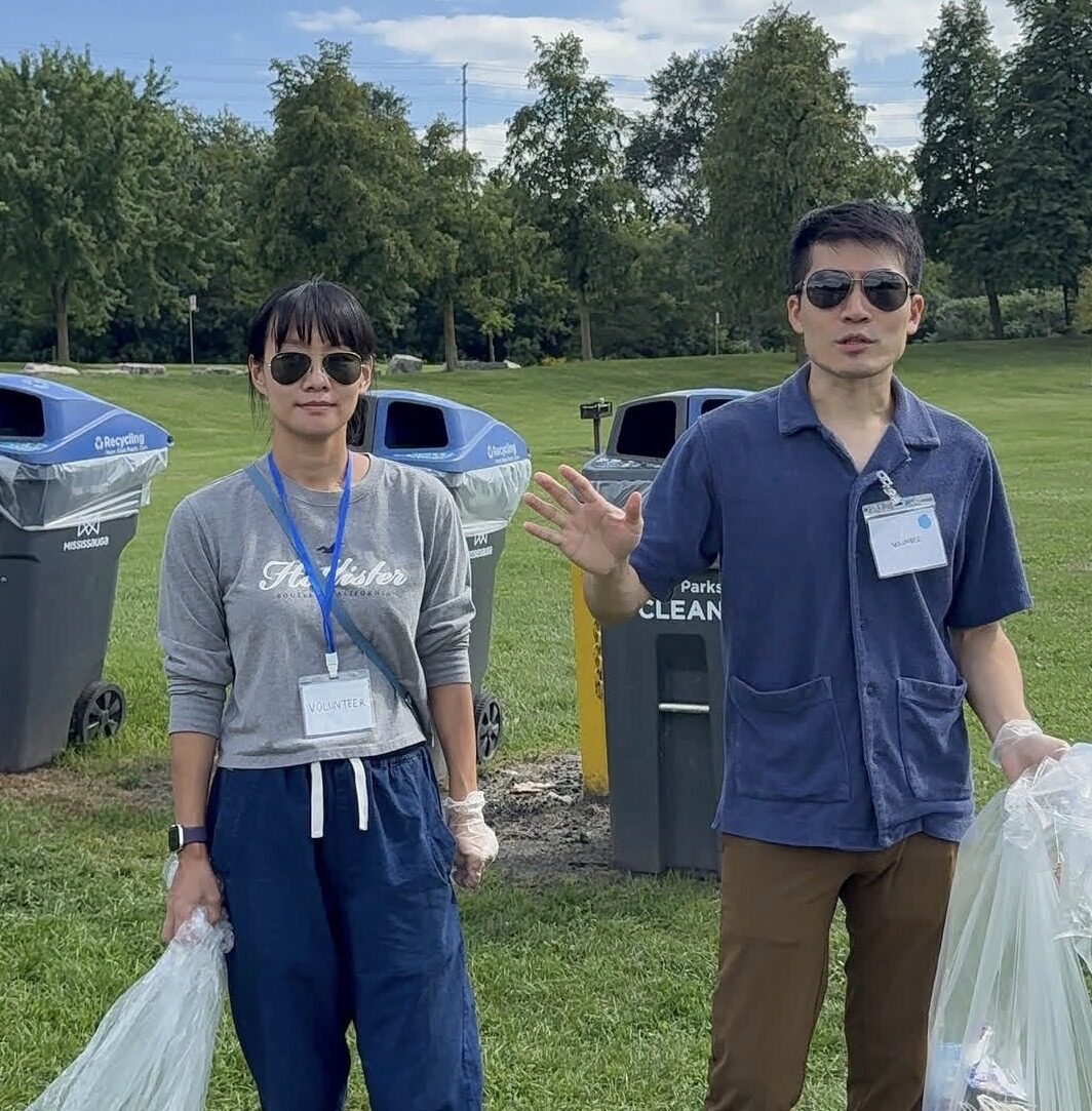 Two MiVolunteer volunteers with gloves and bags at a park cleanup
